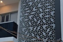 واجهة فيلا مودرن فاخرة بحي النخيل بالرياض تتميز بتكسية من ألواح الألمنيوم المقصوصة بالليزر (CNC) بنقوش هندسية عصرية ولون برونزي، تتدفق منها إضاءة ليد دافئة ومدمجة مع الحجر الطبيعي الأبيض