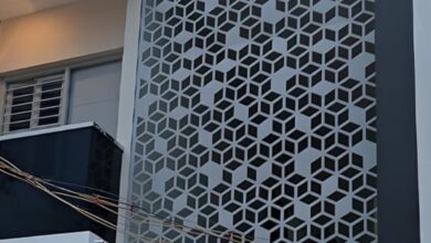 واجهة فيلا مودرن فاخرة بحي النخيل بالرياض تتميز بتكسية من ألواح الألمنيوم المقصوصة بالليزر (CNC) بنقوش هندسية عصرية ولون برونزي، تتدفق منها إضاءة ليد دافئة ومدمجة مع الحجر الطبيعي الأبيض