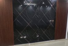 جدار فيلا فاخرة بحي الملقا بالرياض مكسو بلوح بديل الرخام الأبيض ذي العروق الرمادية والذهبية المتصلة مدمج مع شرائح بديل الخشب وإضاءة ليد مخفية دافئة