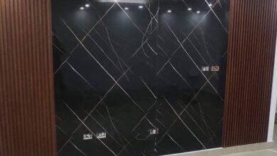جدار فيلا فاخرة بحي الملقا بالرياض مكسو بلوح بديل الرخام الأبيض ذي العروق الرمادية والذهبية المتصلة مدمج مع شرائح بديل الخشب وإضاءة ليد مخفية دافئة